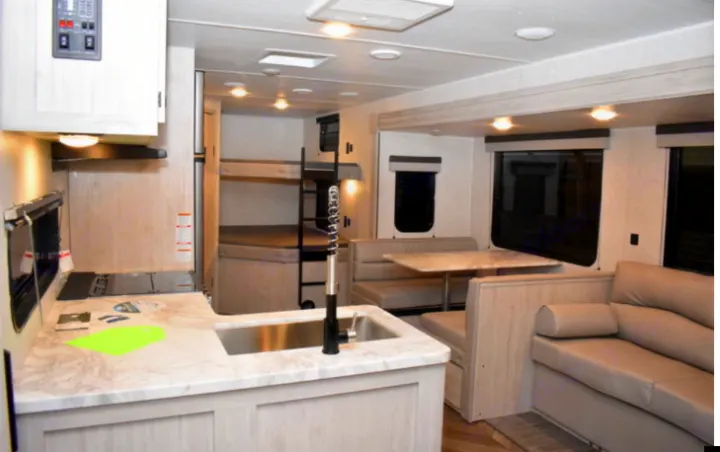 Spacious RV rental interior: modern kitchen, bunk beds, dinette, and sofa offer comfort for family trips.. East to West Other 2022