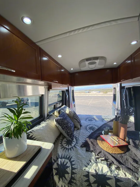 Step into comfort: a spacious RV rental interior featuring a cozy bed, ambient lighting, and open back view.. Pleasure-Way Pleasure-Way Class B 2016