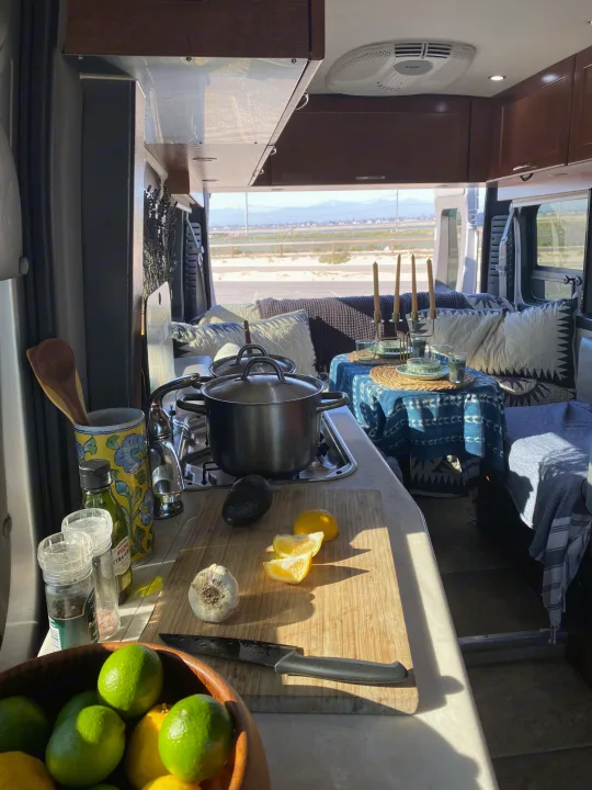 An RV rental's cozy interior, featuring a compact kitchen with cooking ingredients & a dining area ready for a meal with a scenic view.. Pleasure-Way Pleasure-Way Class B 2016