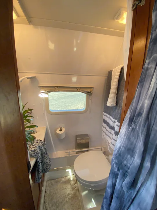 Cozy RV rental bathroom with toilet, shower, sink, window, and towels, perfect for compact travel trailer comfort.. Pleasure-Way Pleasure-Way Class B 2016