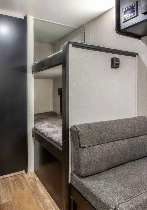RV rental with cozy bunk beds, gray dinette seating, and wood flooring. A functional interior for travel.. Forest River Cherokee Wolf Pup 2022