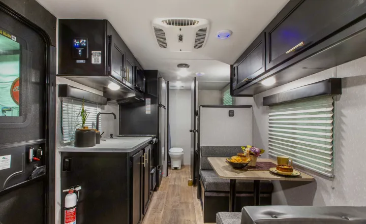 Cozy RV rental interior with a fully equipped kitchen, comfortable dining booth, and visible bathroom entrance.. Forest River Cherokee Wolf Pup 2022