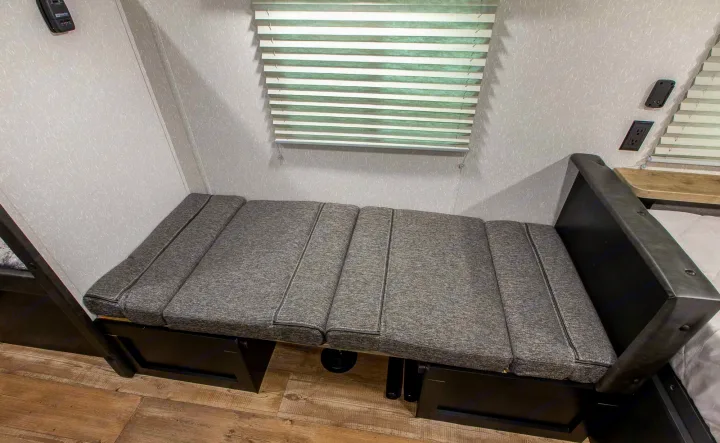 RV rental: Grey cushioned bench seating, often convertible to a bed, with window blinds above.. Forest River Cherokee Wolf Pup 2022