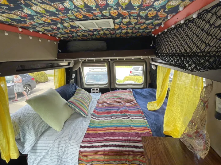 Cozy RV rental interior: colorful bedding, unique ceiling, & sunny curtains.. Ford Econoline 2006