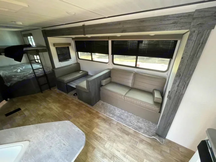 Modern RV rental interior: bunk beds, dinette, and a sofa provide comfortable living space.. Keystone Hideout 2022