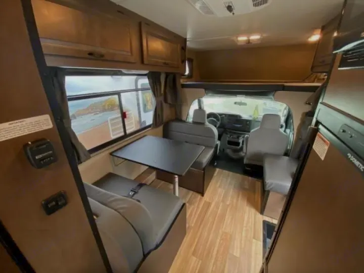 Spacious RV rental interior: dinette, kitchen, driver's cabin, and ocean view from window.. Wayfarer 19 TM 2020