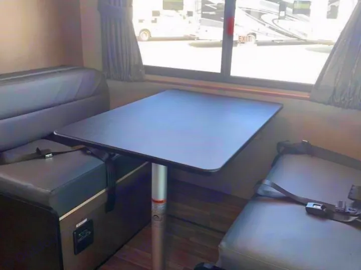 RV rental dinette: a practical setup with a dark table, opposing benches, seatbelts, and window views.. Wayfarer 19 TM 2020