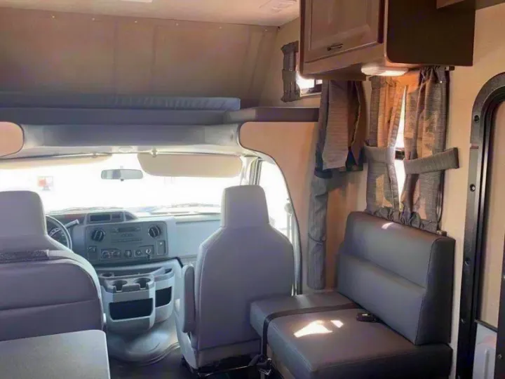 View inside an RV rental: front cabin, overhead sleeping bunk, and a dinette seat on the right.. Wayfarer 19 TM 2020