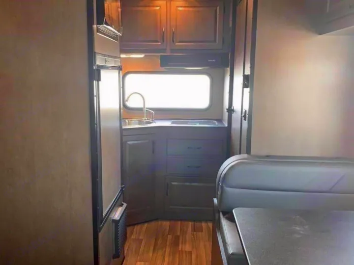 Spacious RV rental interior featuring a compact kitchen with sink, refrigerator, and comfortable dinette area.. Wayfarer 19 TM 2020