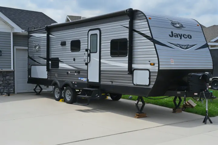 Grey and white Jayco travel trailer parked on a concrete driveway, an ideal RV rental for adventures.. Jayco Jay Flight SLX 2021