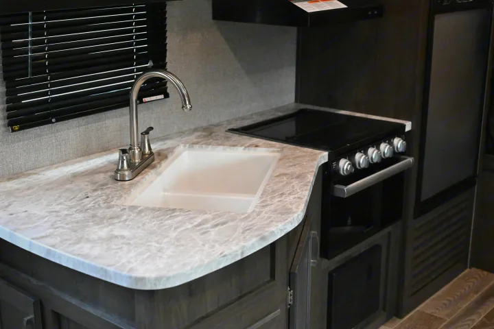 Modern RV kitchen interior features a sink, stovetop, and oven, showcasing amenities for a comfortable rv rental experience.. Jayco Jay Flight SLX 2021