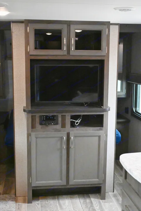 RV rental entertainment center featuring a TV, iRV Technologies stereo, and ample storage cabinets.. Jayco Jay Flight SLX 2021