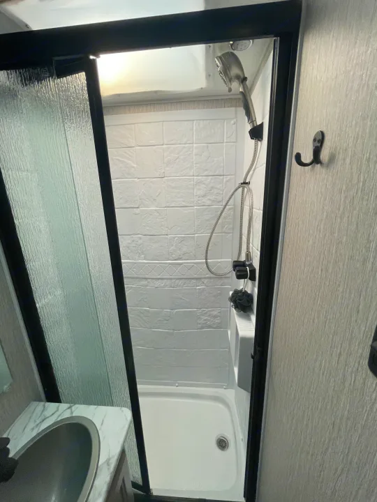 Clean RV rental bathroom: shower, handheld head, skylight, and marble-look vanity with sink.. Other Other 2022