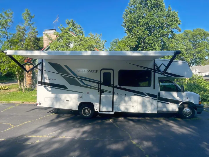 A white Coachmen Freelander RV rental is shown with its side awning fully extended, parked on asphalt.. Other Other 2022