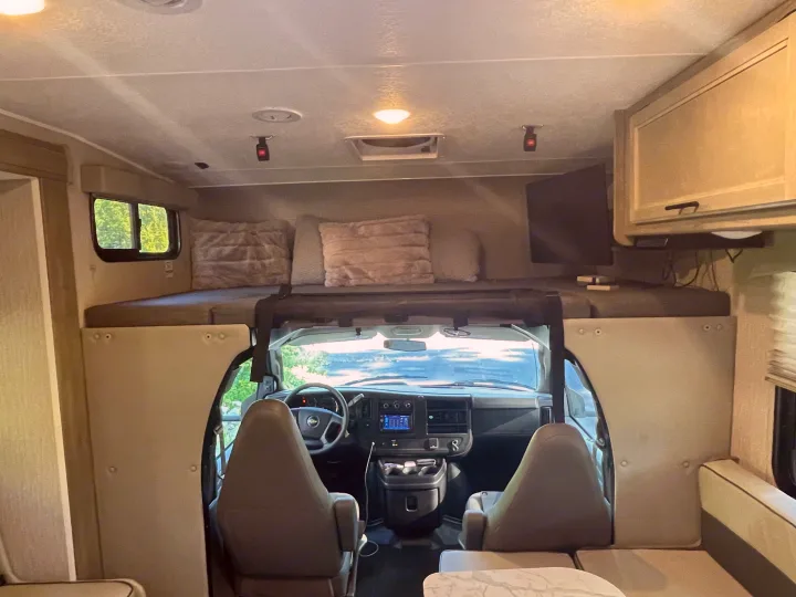 Spacious RV rental interior featuring an overhead bunk, driver's cockpit, and entertainment setup. Ready for your adventure!. Other Other 2022