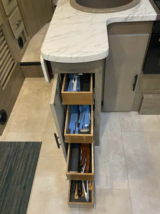 This RV rental kitchen features a marble counter, sink, and four pull-out drawers neatly organizing cutlery and utensils.. Other Other 2022