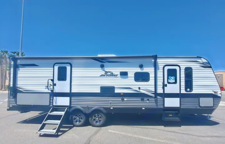 Modern grey & white travel trailer, ideal for RV rental. Steps extended for your next outdoor camping adventure.. Jayco JayFlight 28BHS TT 2022