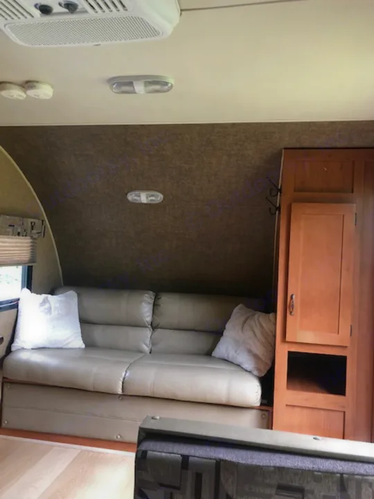 RV rental interior showcasing light brown dinette seating, overhead wooden cabinets, and wall controls.. Forest River Cherokee 2015