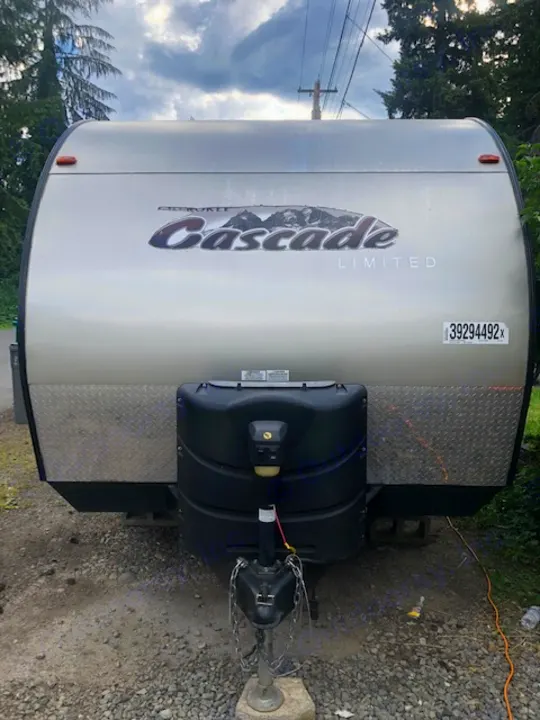 Front of a parked Cascade Limited travel trailer (RV rental), showing the propane tank cover and hitch assembly.. Forest River Cherokee 2015