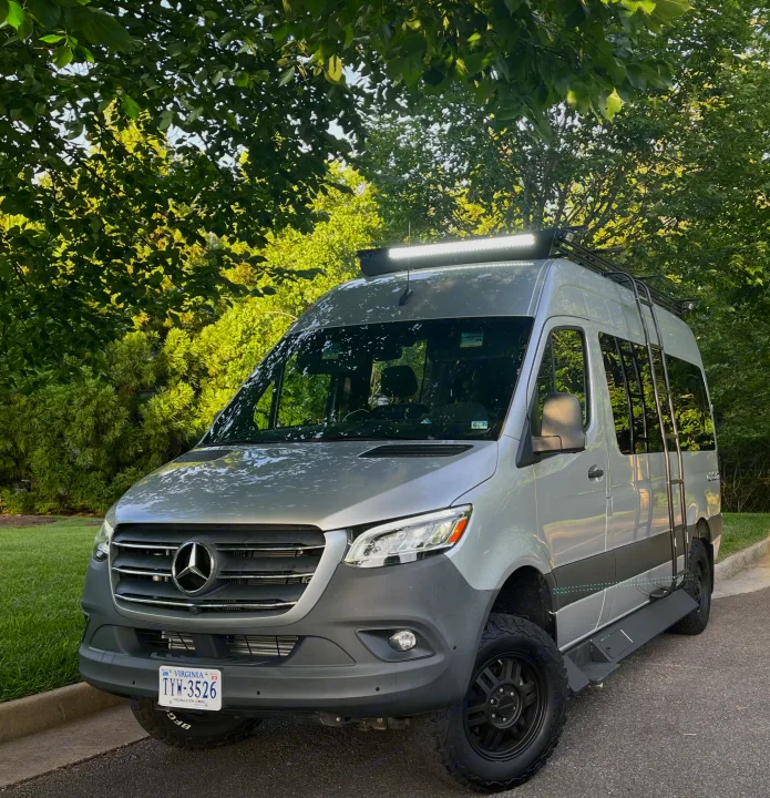 Silver Mercedes Sprinter adventure van with off-road tires & roof rack, ideal for an RV rental road trip.. Tiffin Motorhomes Cahaba 2021