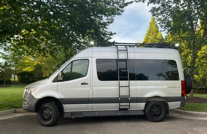 A sleek silver Cahaba RV rental camper van, ready for adventure with its robust tires, roof rack, and bike mount.. Tiffin Motorhomes Cahaba 2021