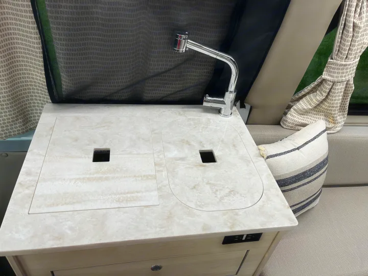 RV rental: Modern RV kitchen showcasing a light stone-look counter, pull-out faucet, induction burner, and power outlets.. Tiffin Motorhomes Cahaba 2021