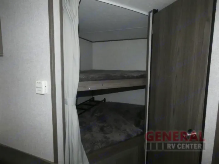 Interior of an RV rental showing stacked bunk beds with a privacy curtain, providing extra sleeping in a camper.. Dutchmen Kodiak Ultra Lite 2021