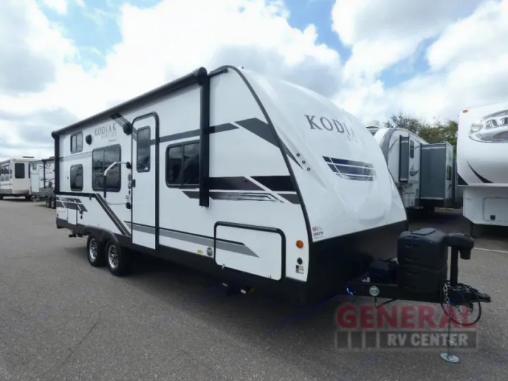 Modern white Kodiak travel trailer, excellent for your next rv rental. Features an awning and multiple windows, parked on a lot.. Dutchmen Kodiak Ultra Lite 2021