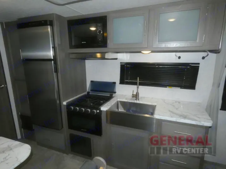 Spacious RV rental kitchen featuring stainless steel fridge, microwave, stove, sink, and ample counter space.. Dutchmen Kodiak Ultra Lite 2021