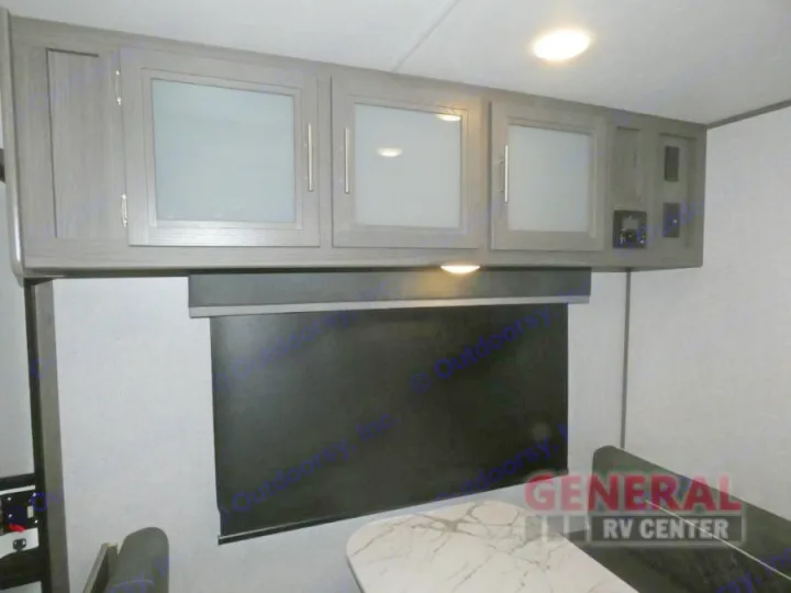 This rv rental features modern overhead cabinets with glass doors, a window with a blind, and a dinette area.. Dutchmen Kodiak Ultra Lite 2021