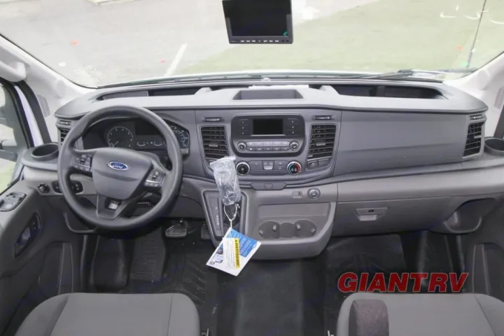 Inside an RV rental van: driver's view of the dashboard, steering wheel, and cabin controls, ready for travel.. Forest River Coachmen Cross Trail XL 2022