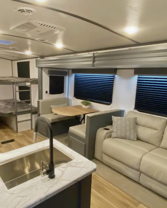 Bright, modern rv rental interior: bunk beds, dinette, sofa, & kitchen counter with sink.. Keystone RV Bullet Ultra Lite 2022