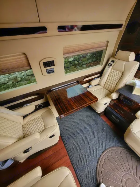 Luxury RV rental interior: spacious cabin with premium seating, wood flooring, and a central table.. Mercedes-Benz Sprinter 2016