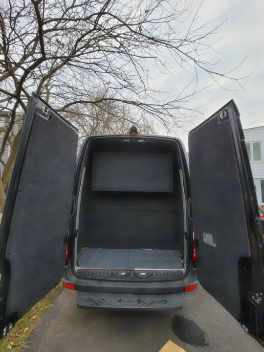 Spacious RV rental van with open rear cargo doors, revealing a carpeted interior and storage shelving for your next trip.. Mercedes-Benz Sprinter 2016