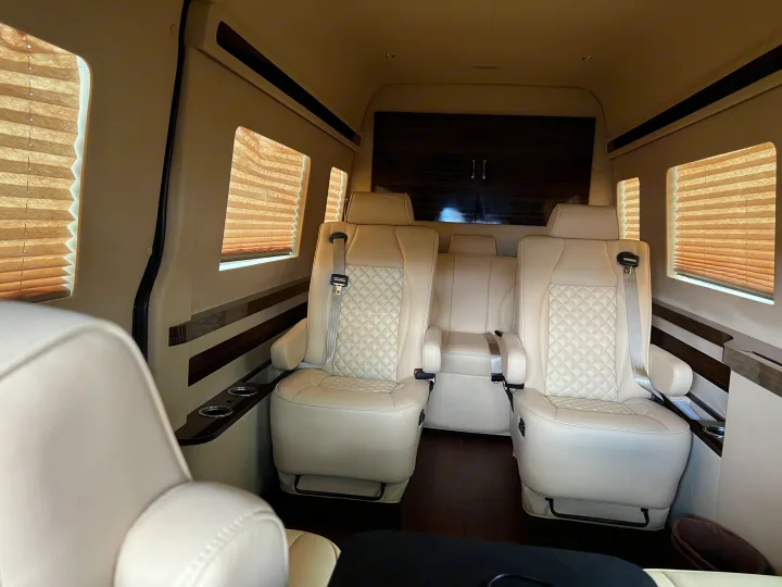 Spacious luxury RV rental interior featuring plush quilted leather captain's chairs, window blinds, and dark wood trim.. Mercedes-Benz Sprinter 2016