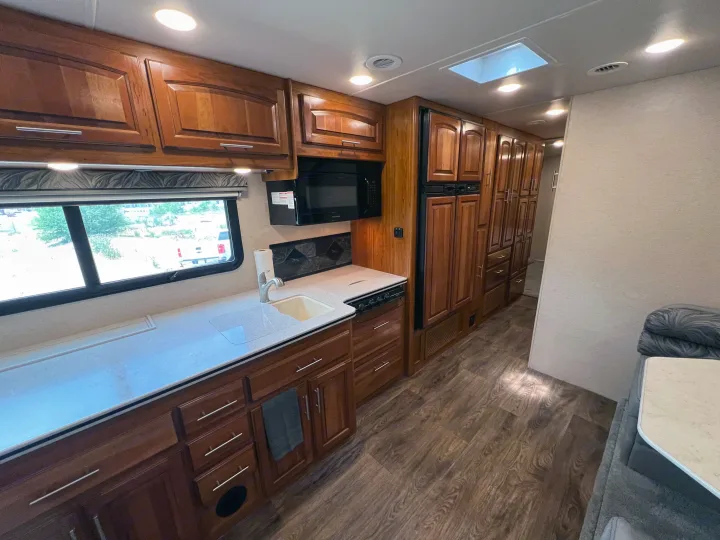 Spacious RV rental kitchen with light counters, wood cabinets, full appliances, and a skylight.. Jayco Precept 2016