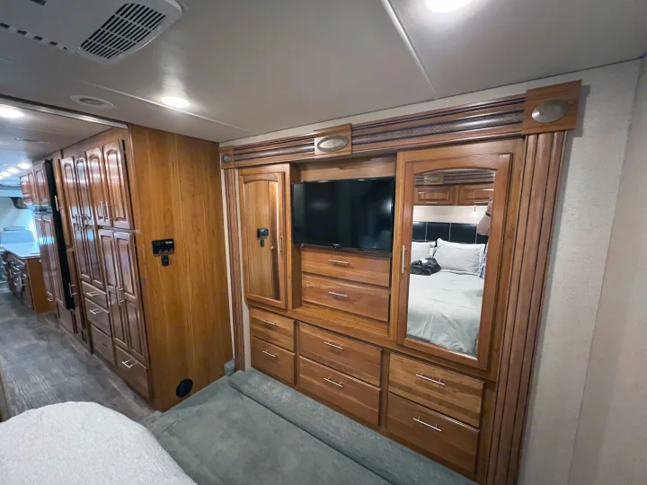 Explore this RV rental's well-appointed interior featuring rich wooden cabinetry, built-in TV, and mirrored bedroom closet.. Jayco Precept 2016