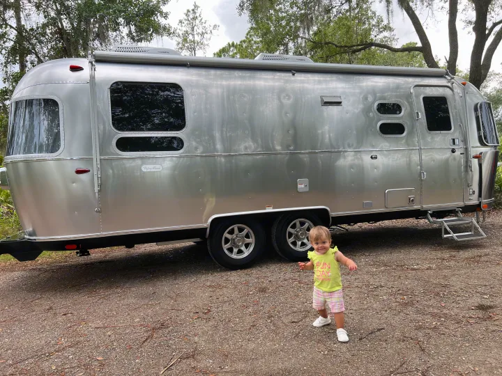 Shiny silver Airstream travel trailer (RV rental) with a happy toddler nearby, ready for family adventures.. Airstream Flying Cloud 25RB 2022