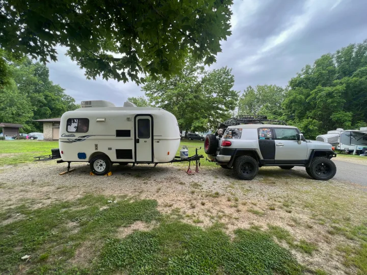 Small white travel trailer and FJ Cruiser parked at a gravel campsite. Ideal RV rental setup for camping trips!. Casita 17' Spirit Deluxe 2010