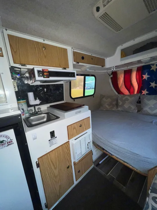 Cozy RV rental interior with kitchenette, bed, and flag decor, ideal for travel adventures.. Casita 17' Spirit Deluxe 2010
