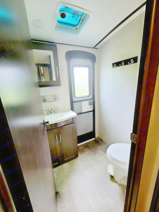 Inside an RV rental bathroom: features a vanity, sink, toilet, door with window, and ceiling vent. Compact and functional.. Crossroads RV Sunset Trail Super Lite 2018