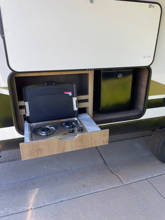 This RV rental features a pull-out outdoor kitchen with a two-burner stove and mini-fridge, ideal for camping.. Grand Design Imagine XLS 2021