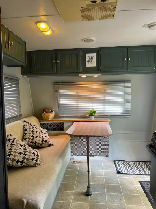 Cozy, renovated RV rental interior with bench seating, dining table, and modern decor, perfect for your next adventure.. Dutchmen Sport 2004