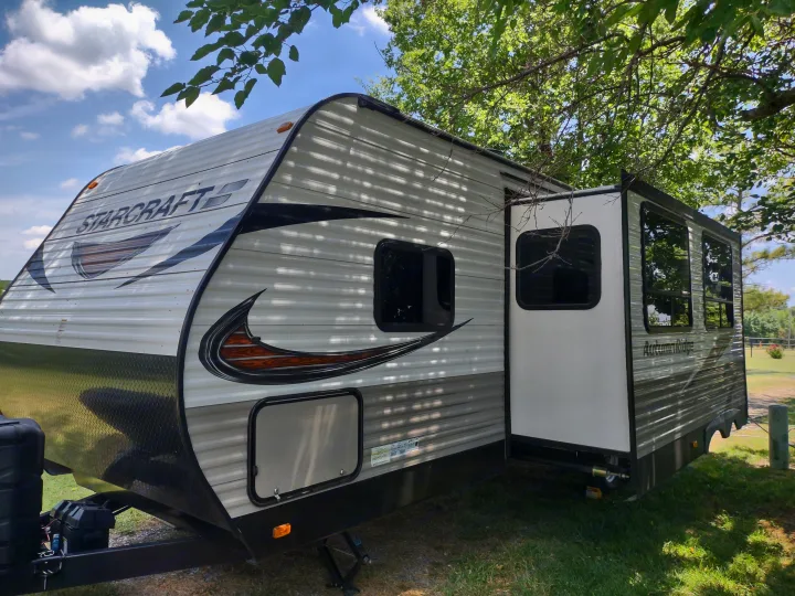A StarCraft Autumn Ridge RV rental with an extended side slide-out, parked under trees on a sunny day.. Starcraft Autumn Ridge Outfitter 2019