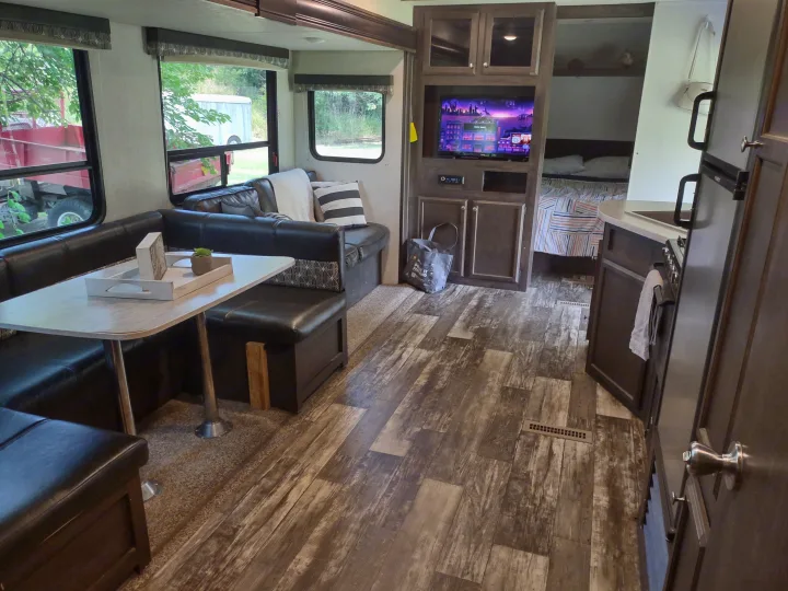 Modern RV rental interior with a cozy dinette, entertainment center, compact kitchen, and inviting bedroom.. Starcraft Autumn Ridge Outfitter 2019