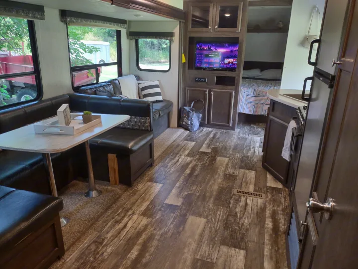 Spacious RV rental interior featuring a comfy dinette, kitchen, and entertainment center with TV, leading to a cozy bedroom area.. Starcraft Autumn Ridge Outfitter 2019