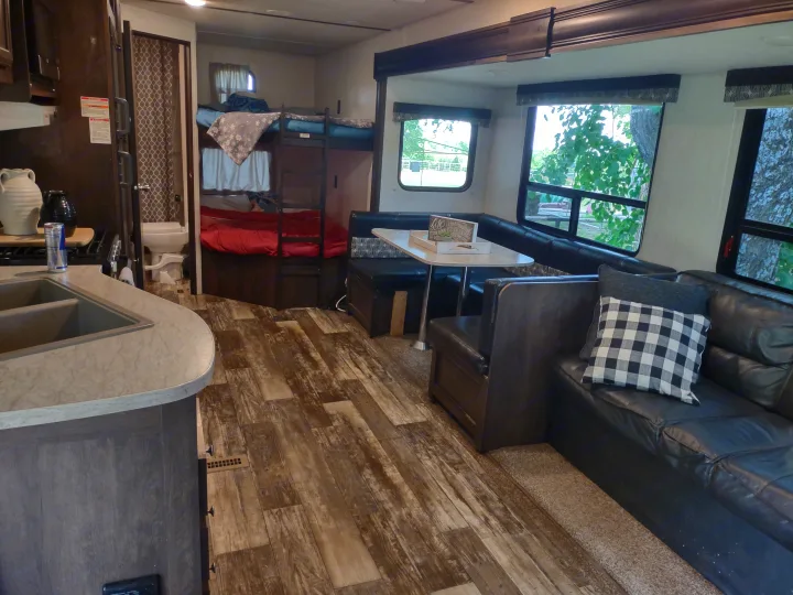Spacious RV rental interior featuring kitchen, bunk beds, dinette, and sofa. Ideal for comfortable travel.. Starcraft Autumn Ridge Outfitter 2019
