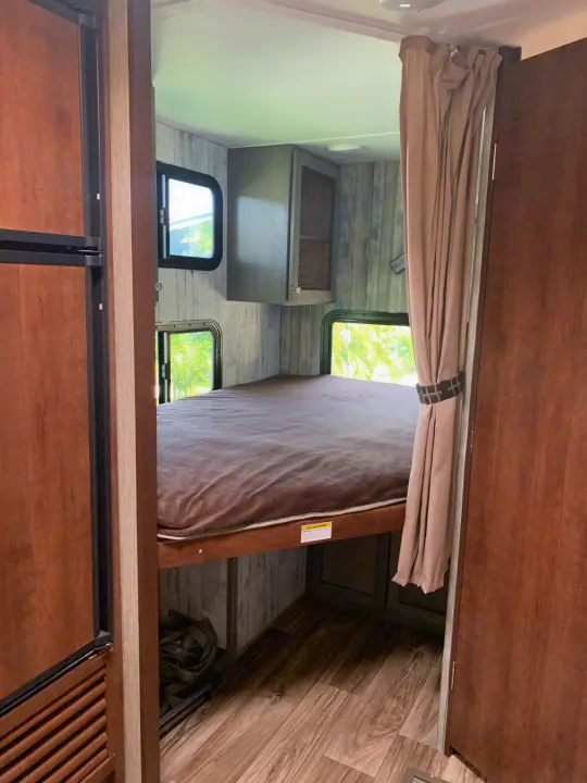 Cozy RV rental interior featuring a comfortable bunk bed, ideal for a compact sleeping space with scenic views.. Keystone RV Passport Elite 2017