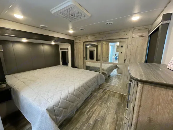 Experience comfort in this RV rental's bedroom, featuring a large bed, mirrored closet, and modern interior design.. Keystone RV Alpine Avalanche Edition 2025