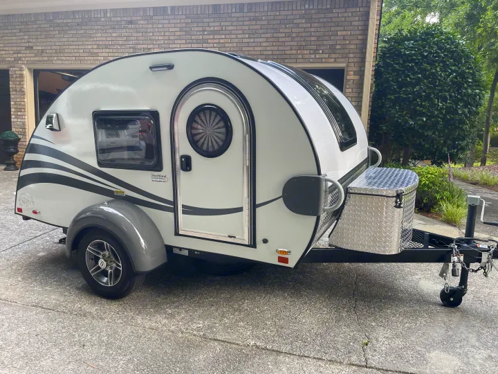 This white teardrop RV rental, with a distinct rounded design and diamond plate storage box, is ready for your next trip.. nuCamp RV T@G XL 6 wide 2022